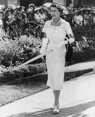 Queen Elizabeth II in hat, gloves, matching shoes, pearls, with umbrella