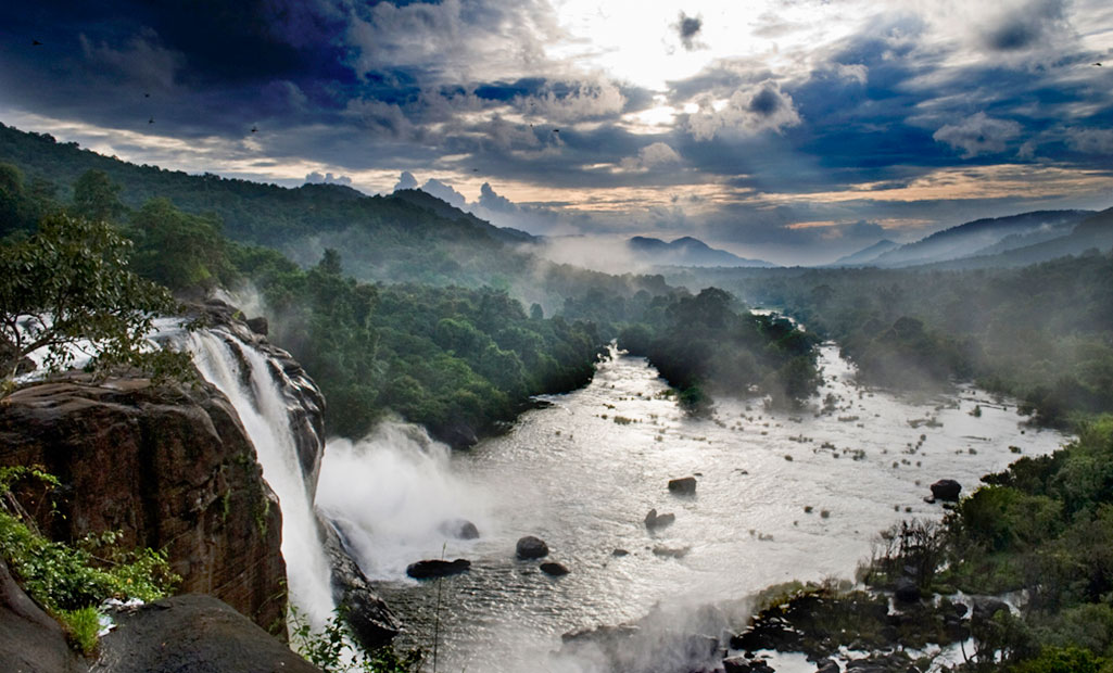 Kerala, India, waterfall and green mountains during monsoon rainy season.