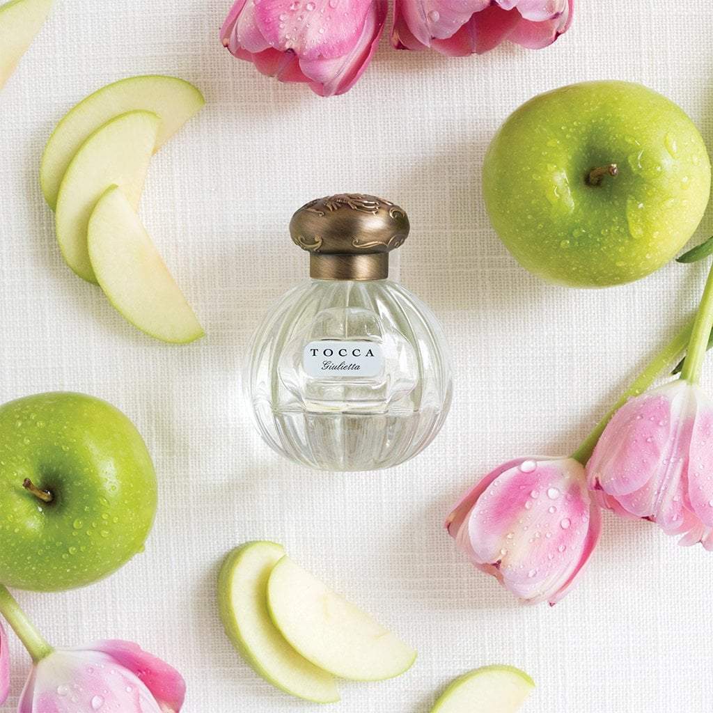 Bottle of Giulietta eau de parfum from Tocca with pink tulips and green apples