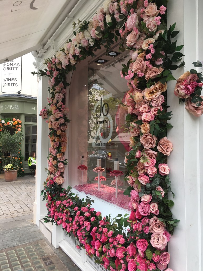 Storefront of Jo Loves fragrance boutique, decorated with roses.